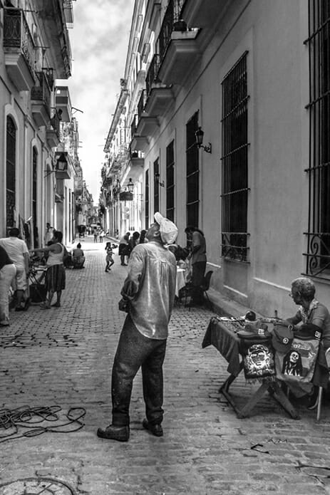 man looking up at building in alleyway of small town street photography portrait city people camera subject light how to tutorial guide