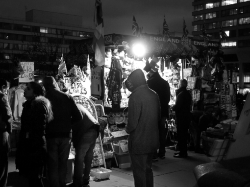 people in a busy night market looking at stalls black and white street photography portrait city people camera subject light how to tutorial guide