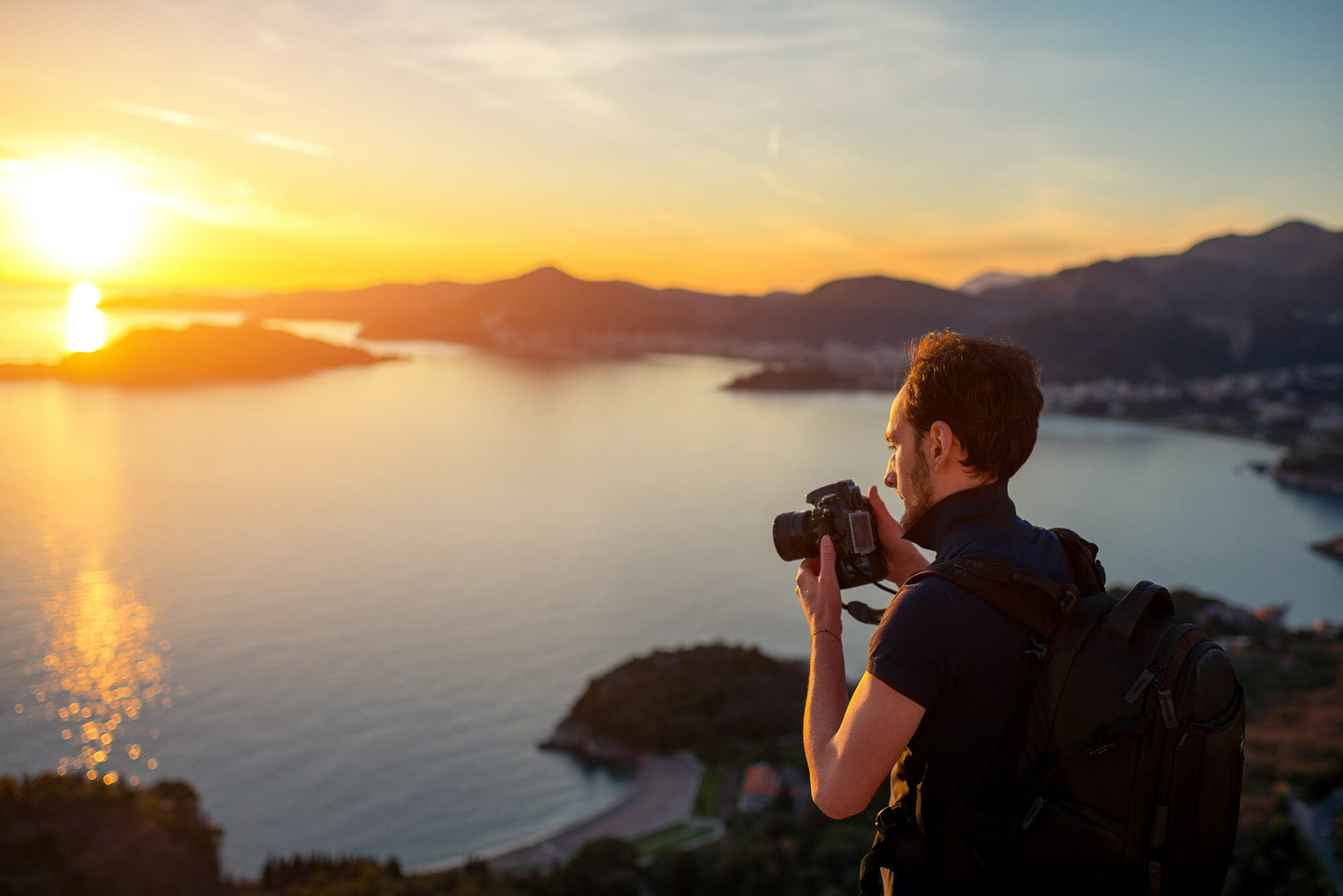man camera cliff top sunset polo shirt wind taking photographs of landscape