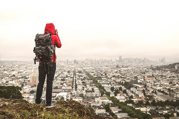 photographer on cliff edge overlooking city