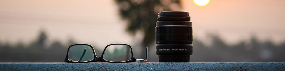 glasses and a macro lens with a sunset behind