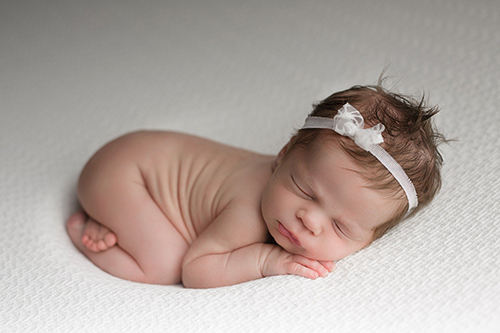 baby lying on white blanket
