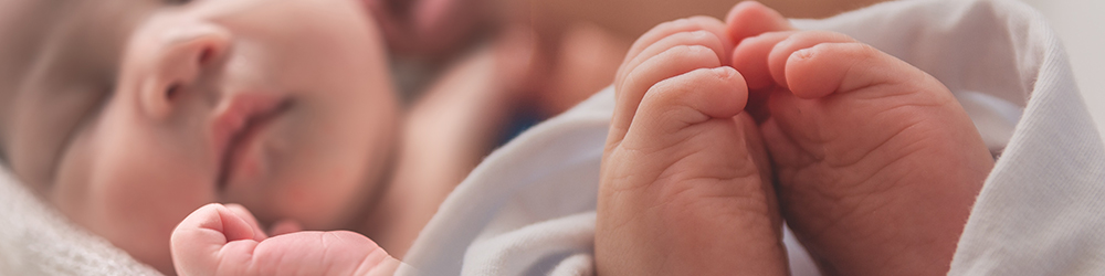 hands and feet of a baby in white blanket