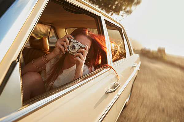 summer photography tips blog 4 female leaning out of a car window taking a picture