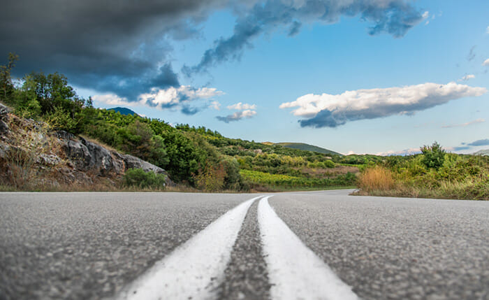 Low,Angle,Shot,Of,Road,And,Green,Hills,With,Blue
