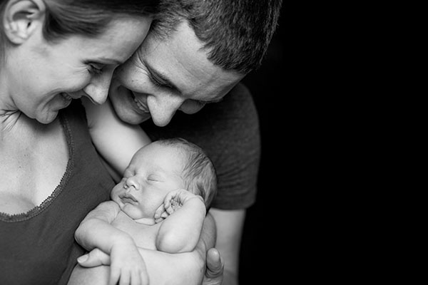 Beautiful,Mother,And,Father,Smiling,Holding,Their,Newborn,Baby,Boy